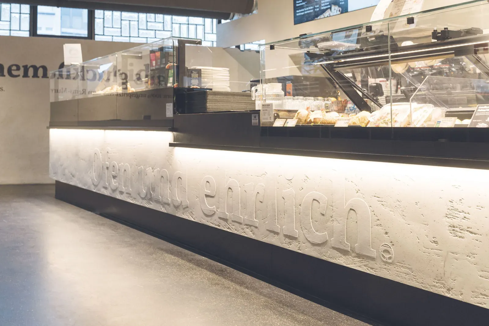 Die Thekenfront im Bäckerei-Café Waiblingen, in den Putz ist Ofen und ehrlich. als Relief eingearbeitet