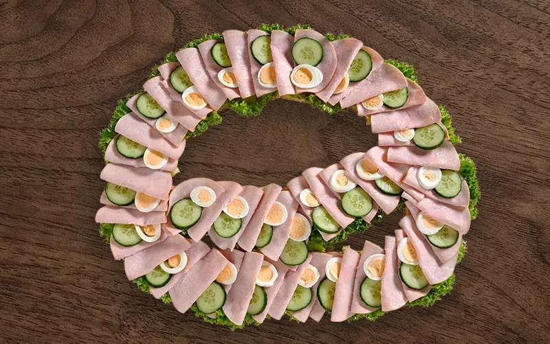 Riesen-Brezel von oben, offen: gefächerter Schinken, dazwischen Scheiben von Gurke und hartem Ei.