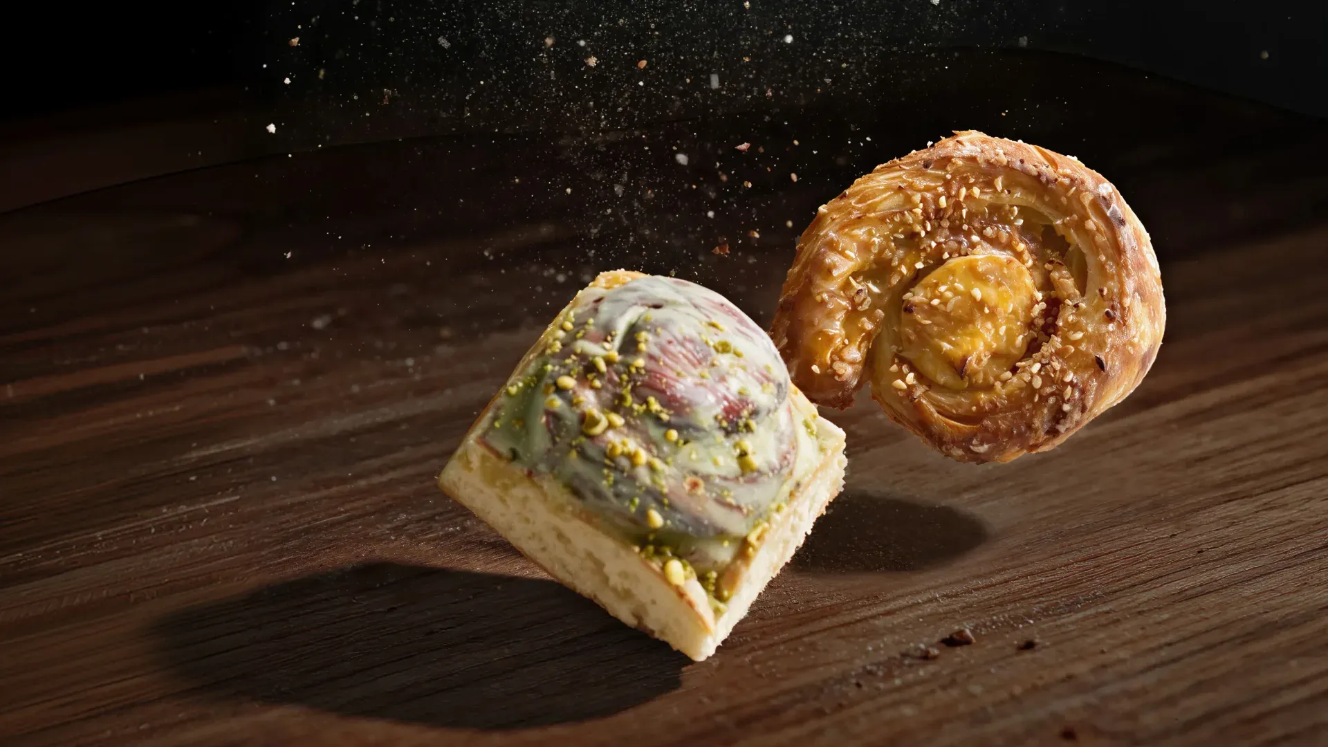 Eine Pistazienschnecke im Blech und eine Cheesecake-Schnecke fallen über eine Holzplatte