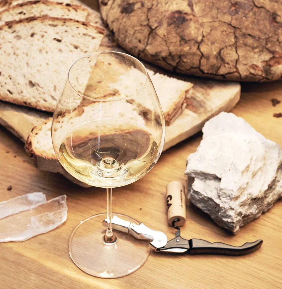 Weinglas mit Weißwein und Brot im Hintergrund